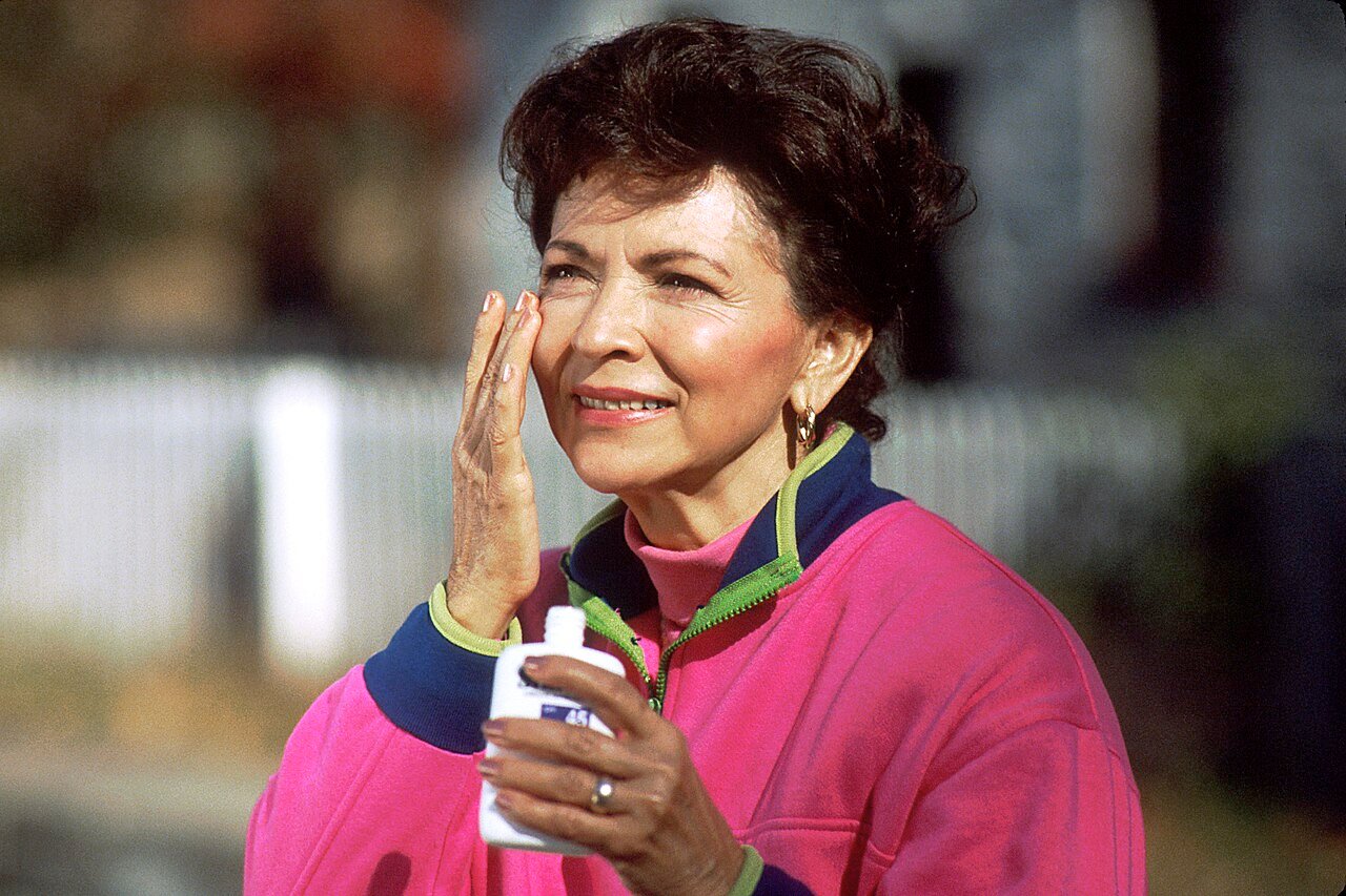 A woman applying sunscreen to her face